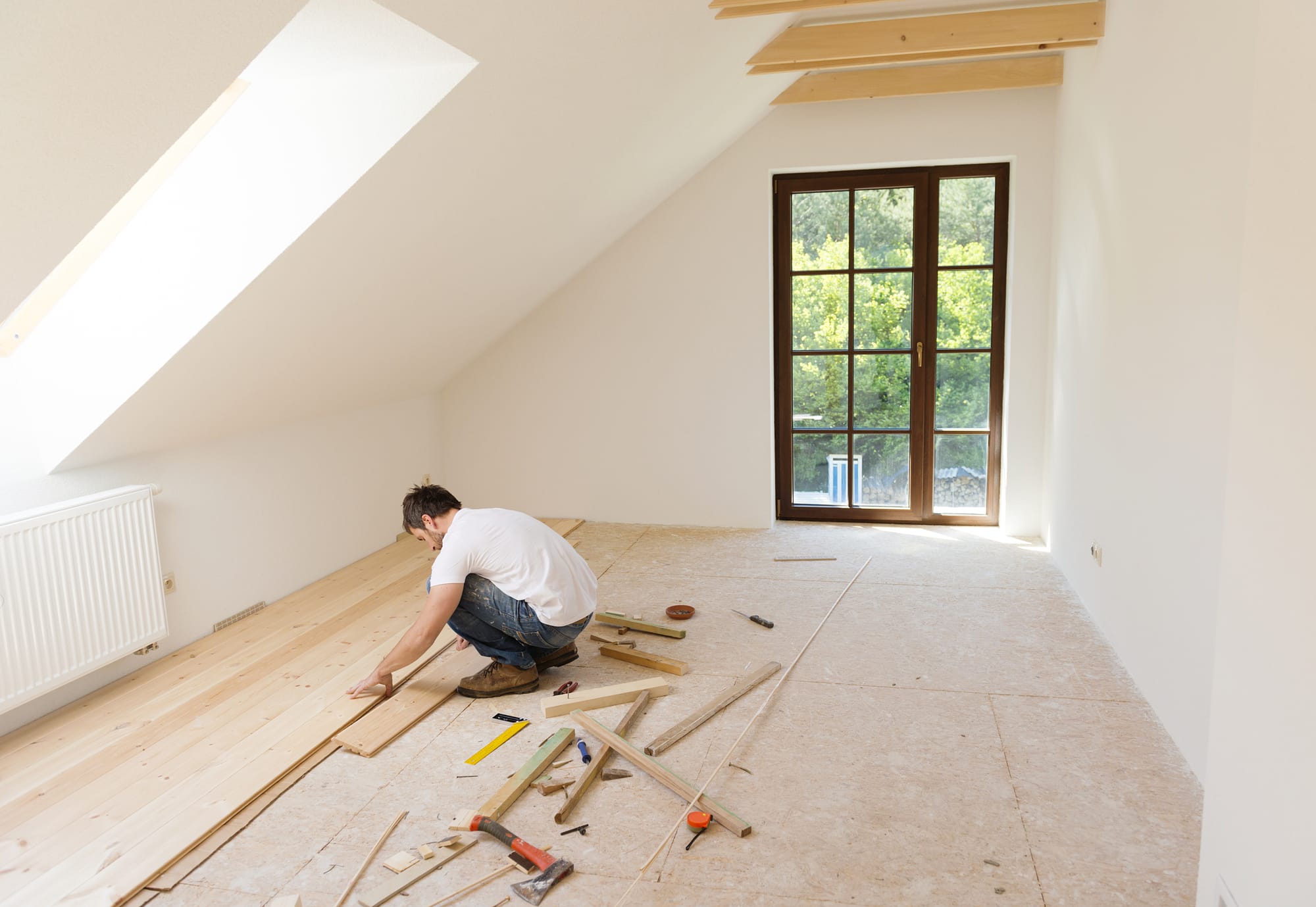 Vakman legt een nieuwe vloer in een lichte zolderkamer