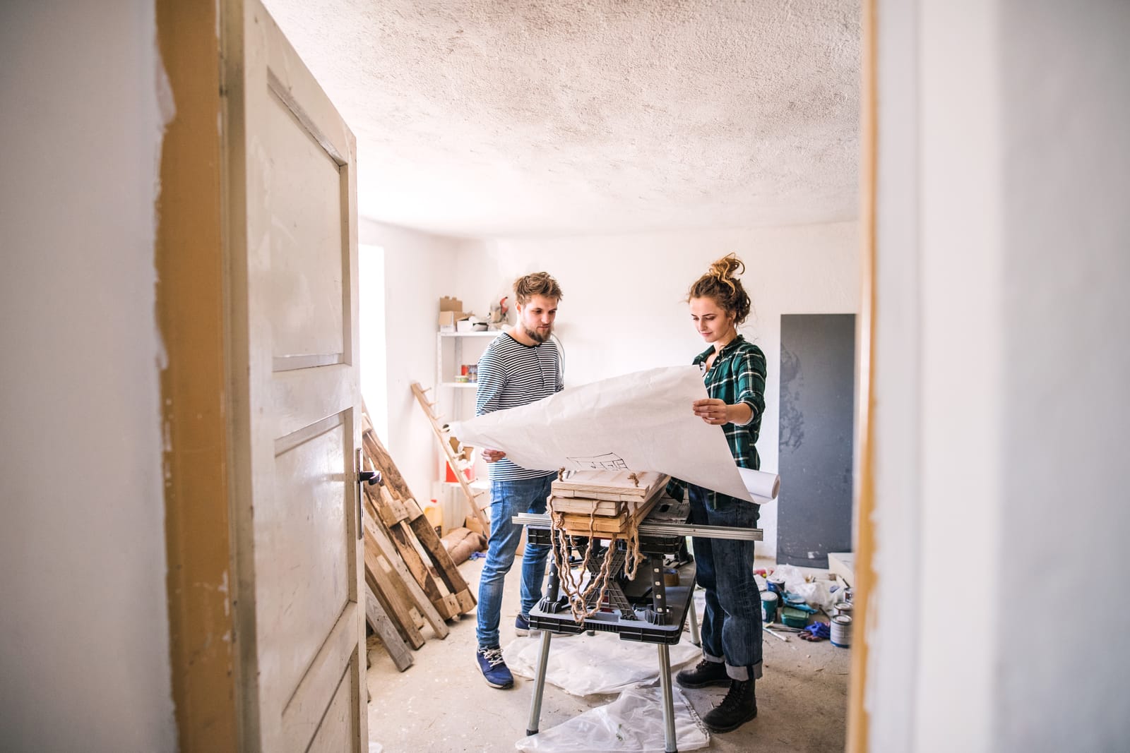 Vakman en klant bekijken de plannen in een huis dat verbouwd wordt