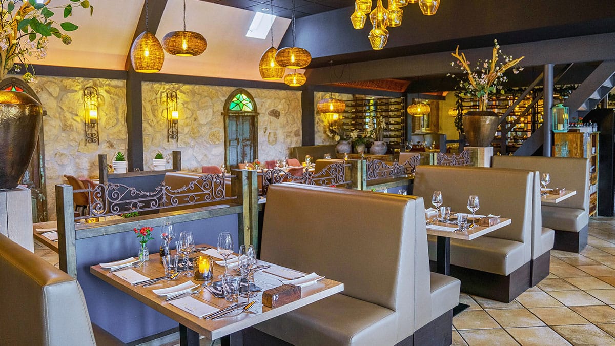 Restaurant met zitbanken, gedekte tafels en hanglampen