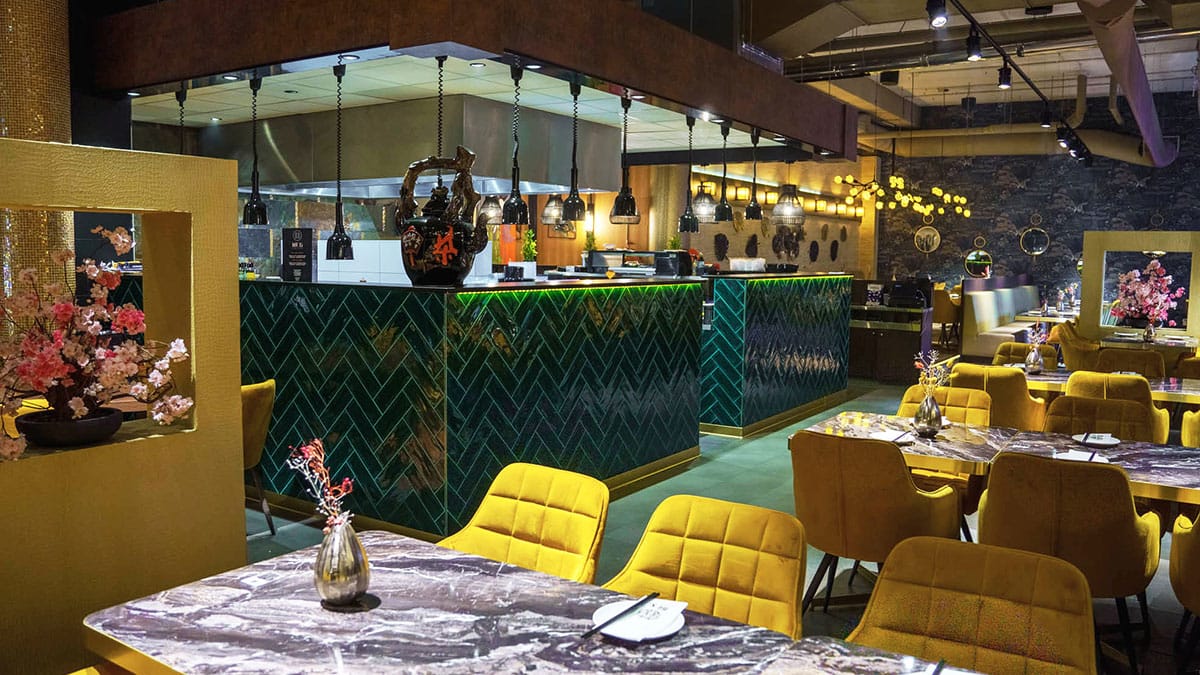 Restaurant met een groen betegelde bar en gele stoelen