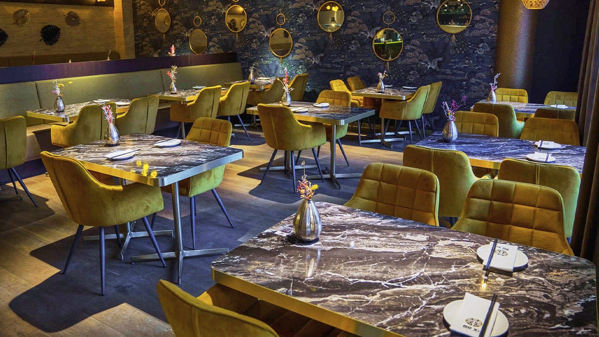 Restaurant met marmeren tafels en gele fluwelen stoelen