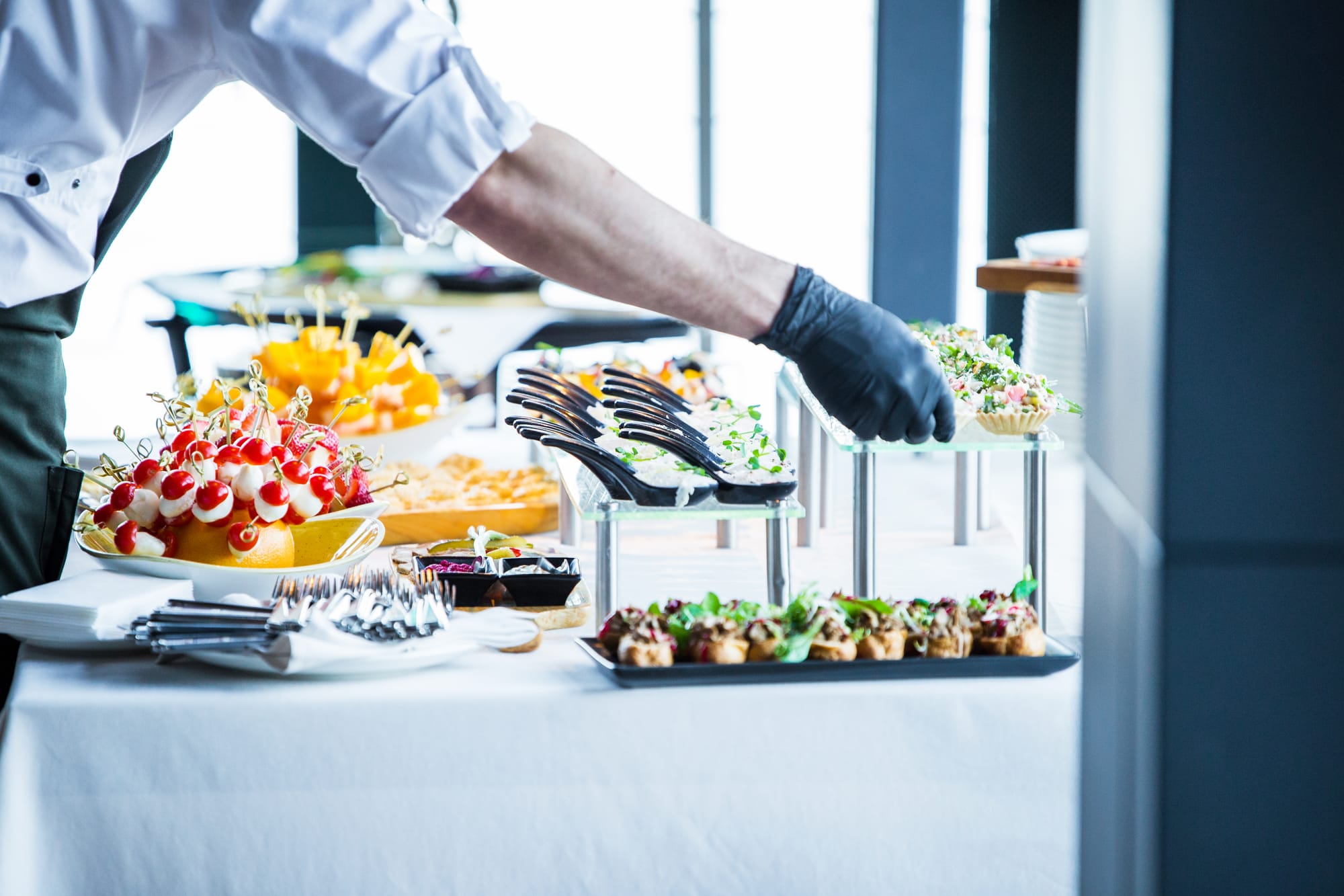 Medewerker in handschoenen legt tangen klaar bij een buffet