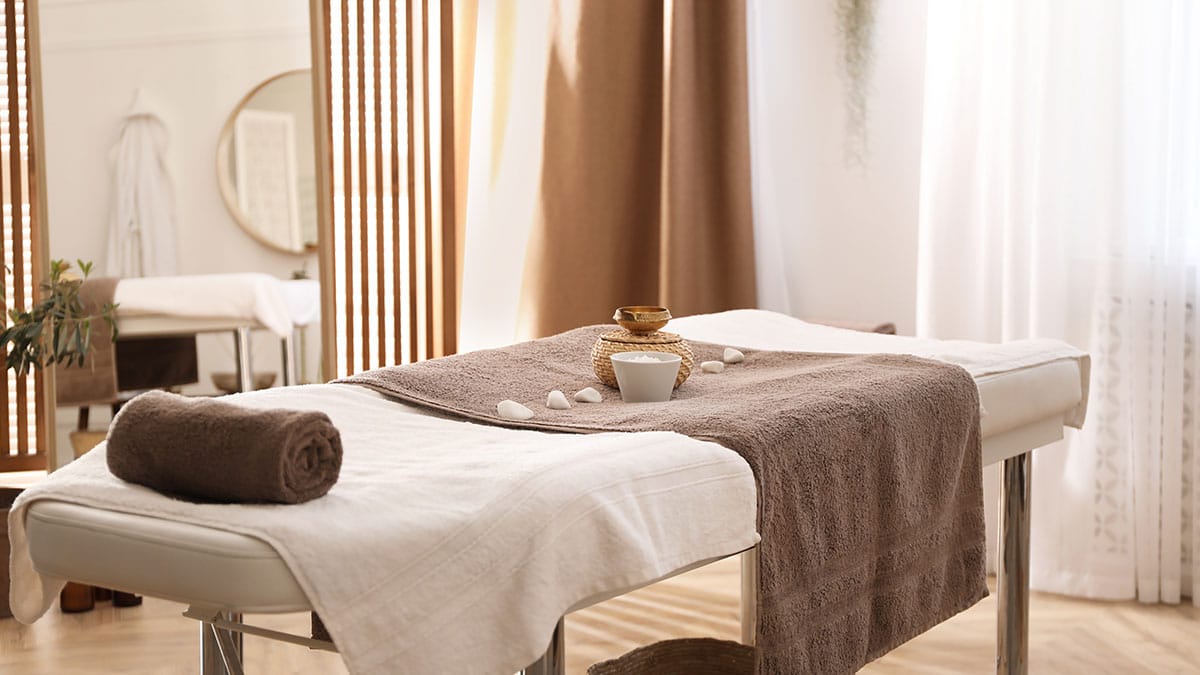 Massagetafel met handdoeken en stenen in een rustige ruimte