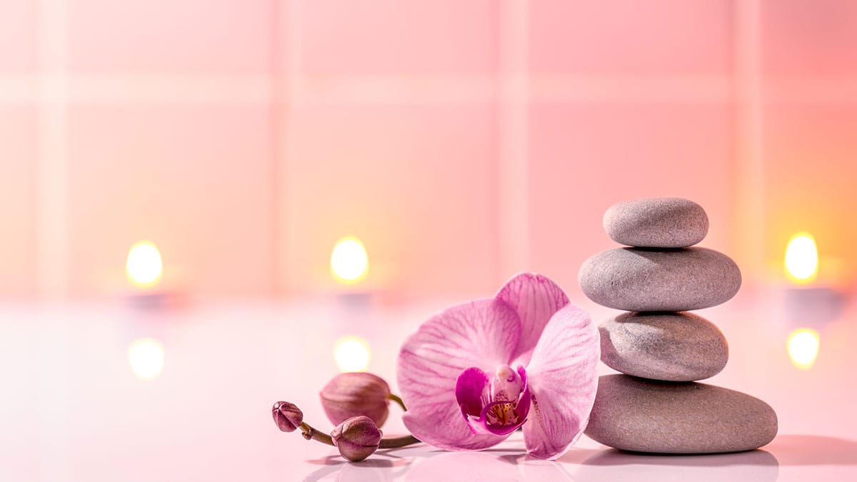 Orchidee en gestapelde stenen bij kaarslicht