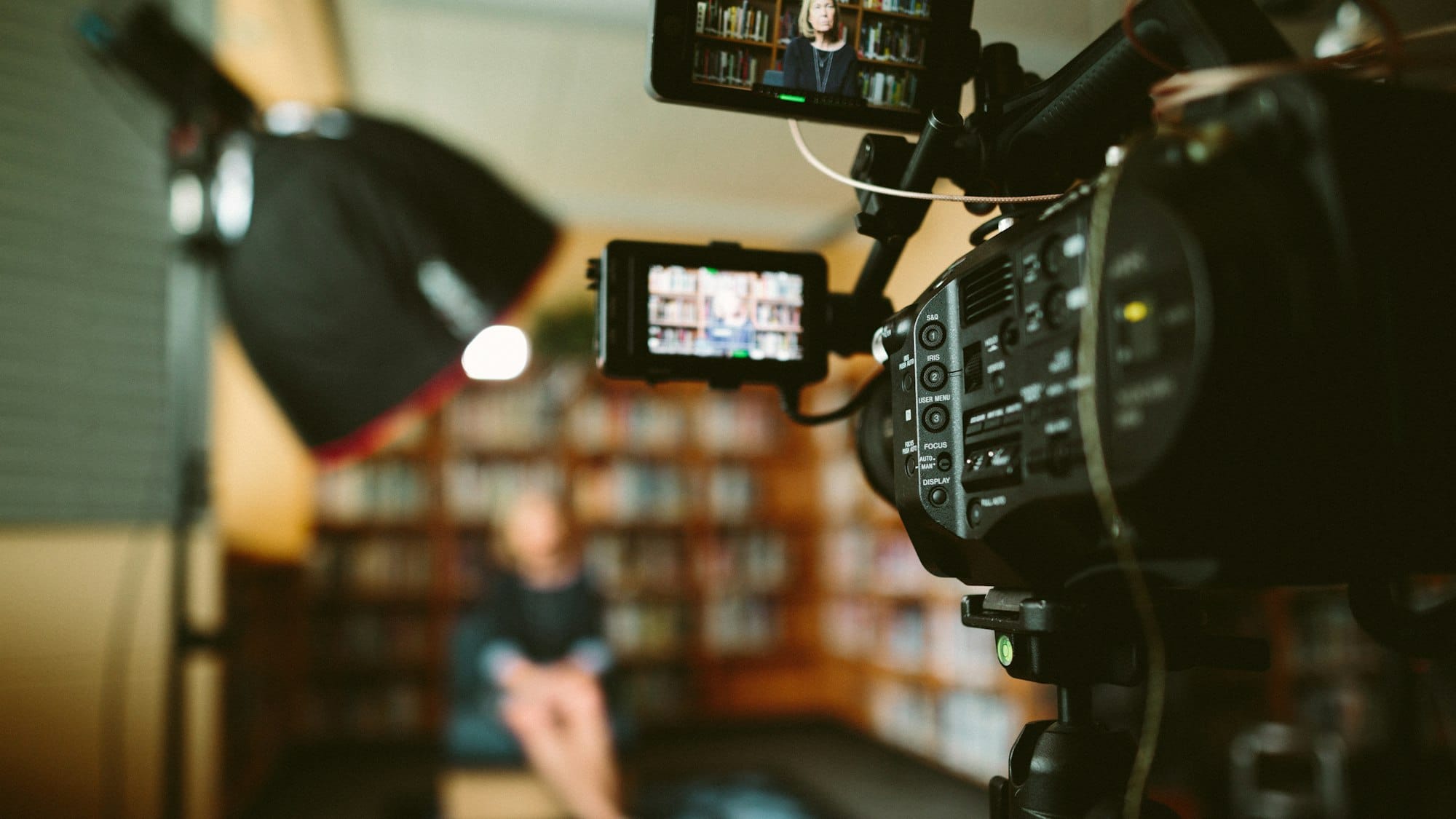 Filmcamera met monitor neemt een interview op in een bibliotheek