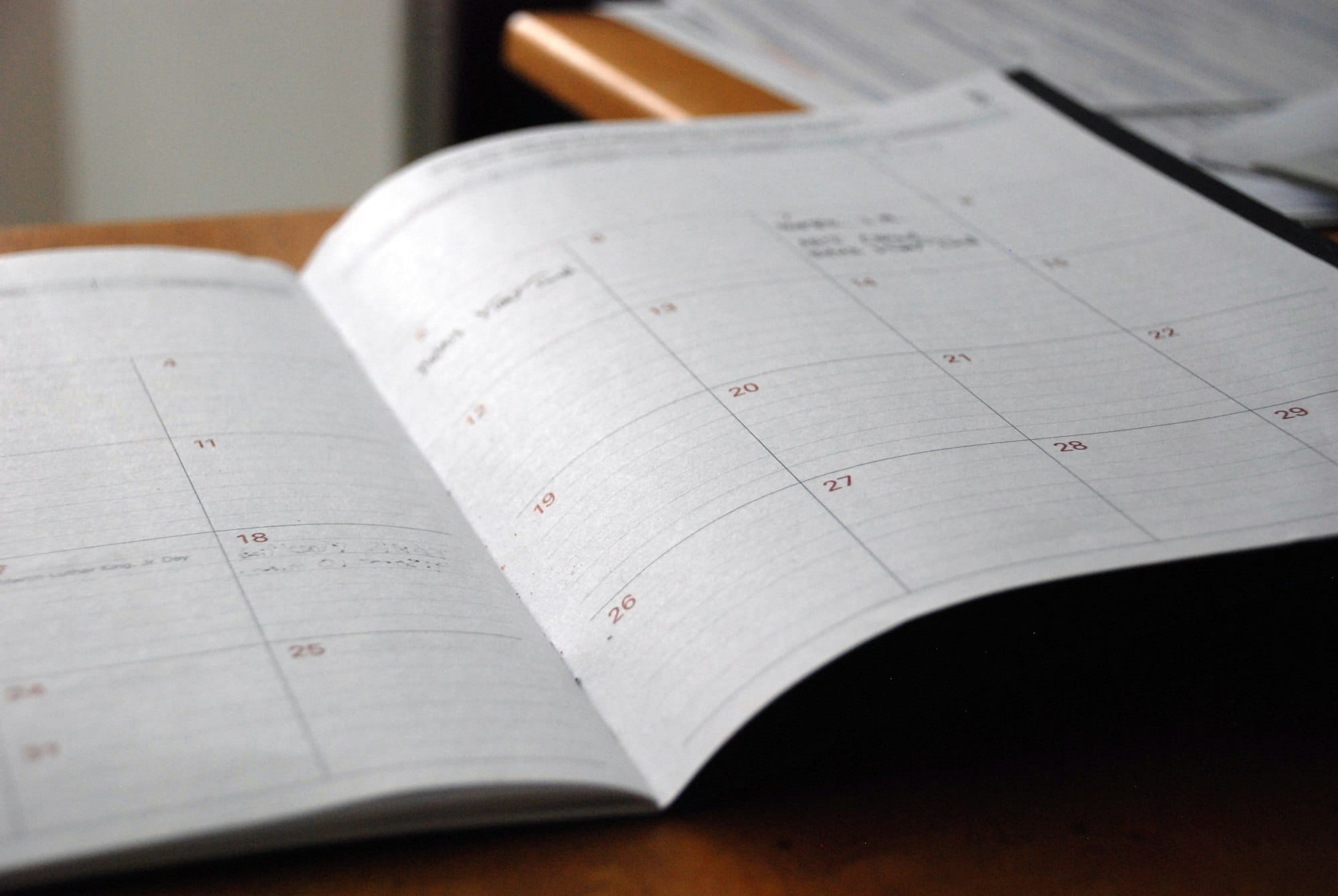 Opengeslagen maandplanner op een houten bureau in zacht daglicht