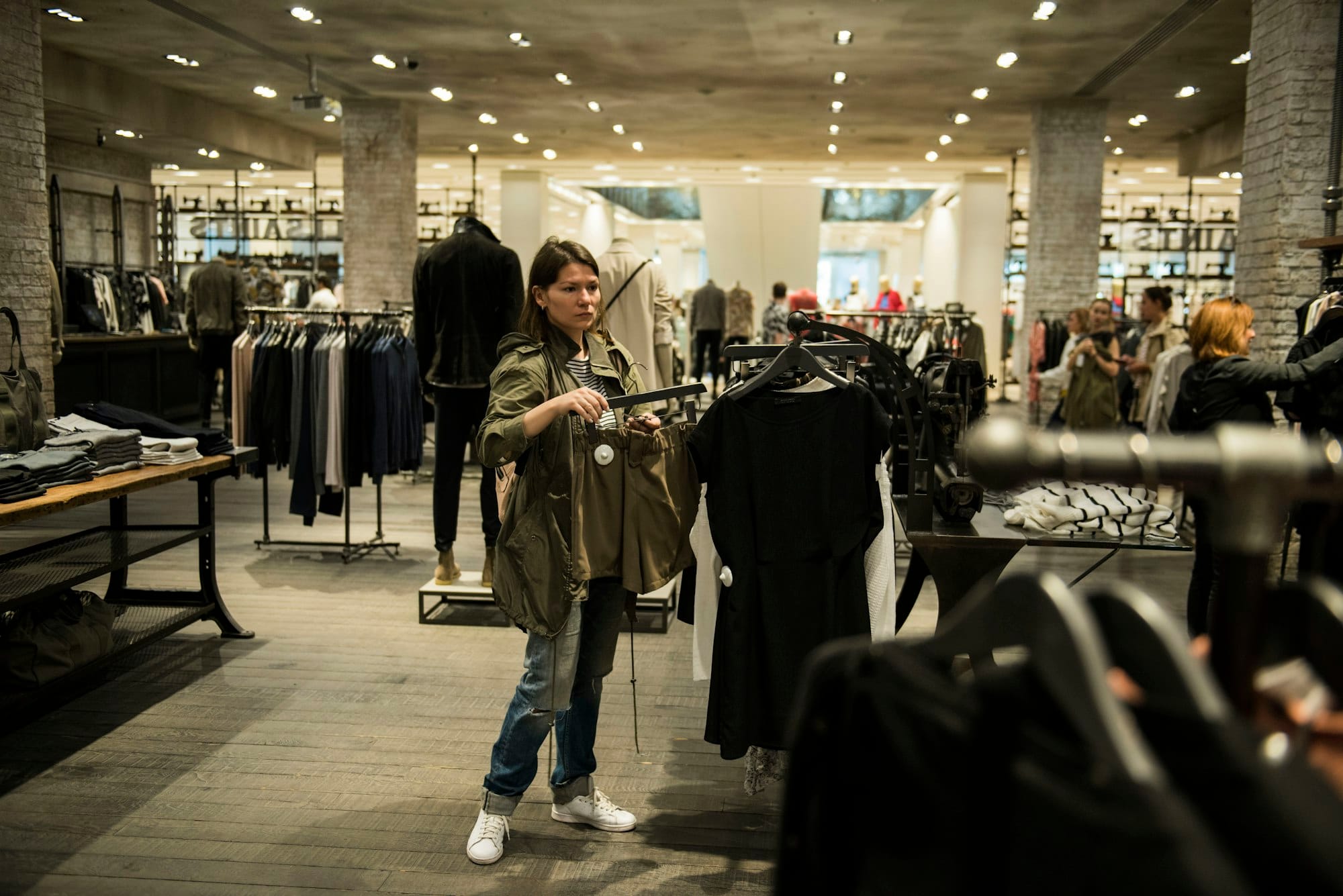 Vrouw bekijkt kleding aan een rek in een ruime winkel