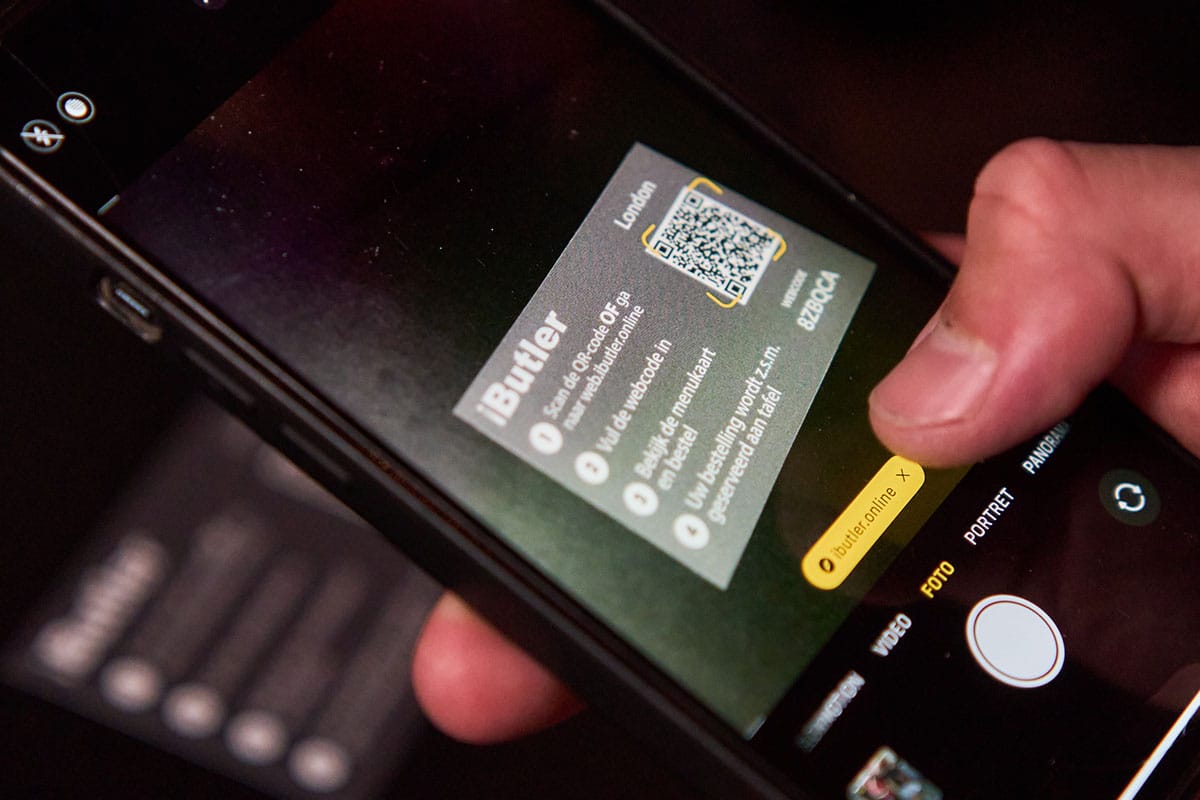 Telefoon scant de QR-code van iButler op een tafelkaart