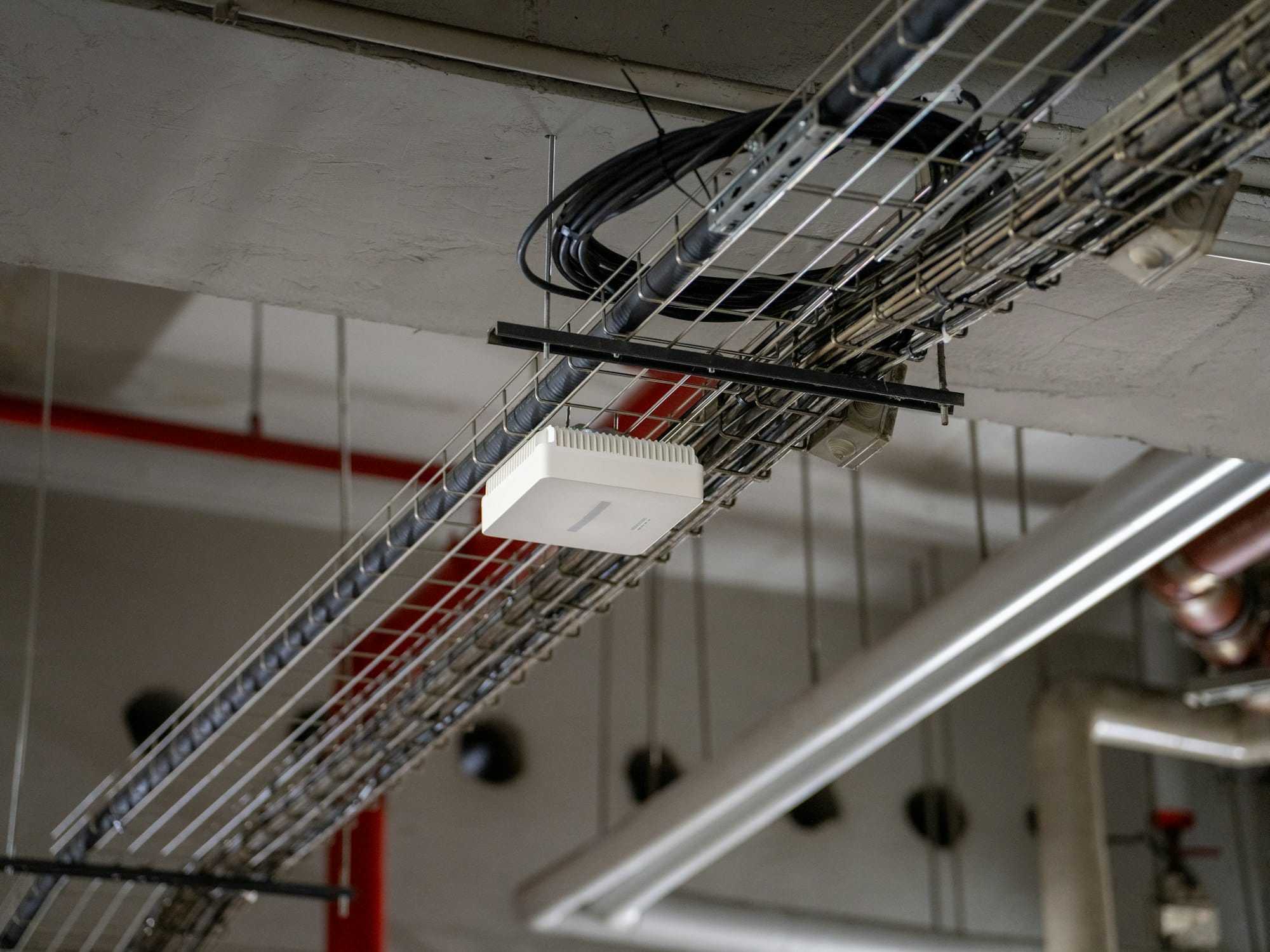 Wifi-accesspoint aan een kabelgoot onder een industrieel plafond