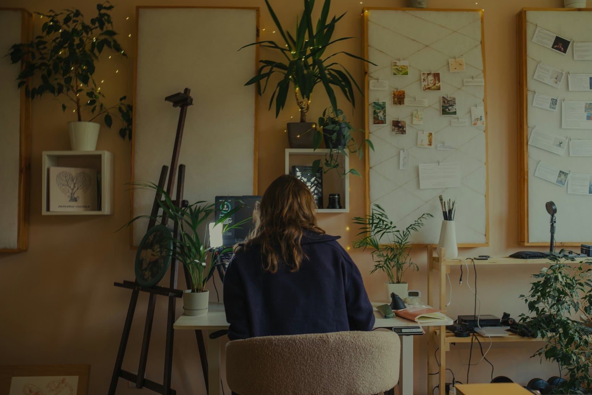 Vrouw werkt aan een bureau in een warme studio vol planten