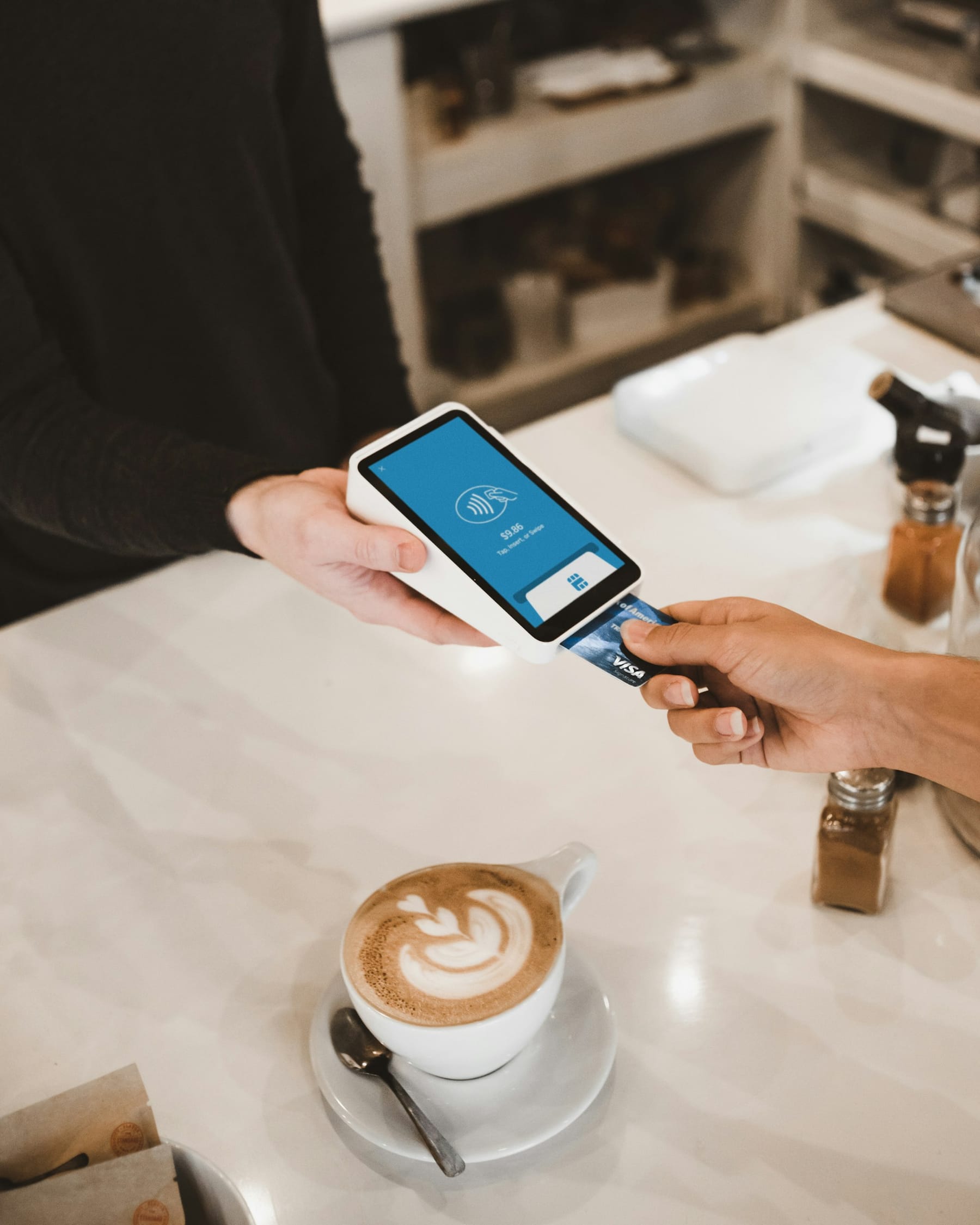 Gast betaalt met een pinpas aan een pinautomaat in een café
