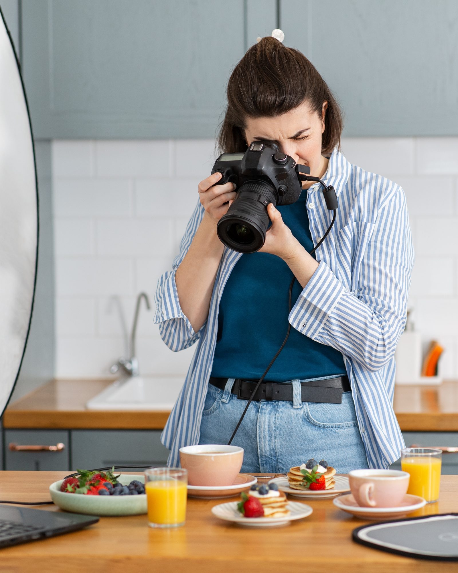 Fotograaf maakt foto's van een ontbijt in een keuken, met reflectiescherm en statief